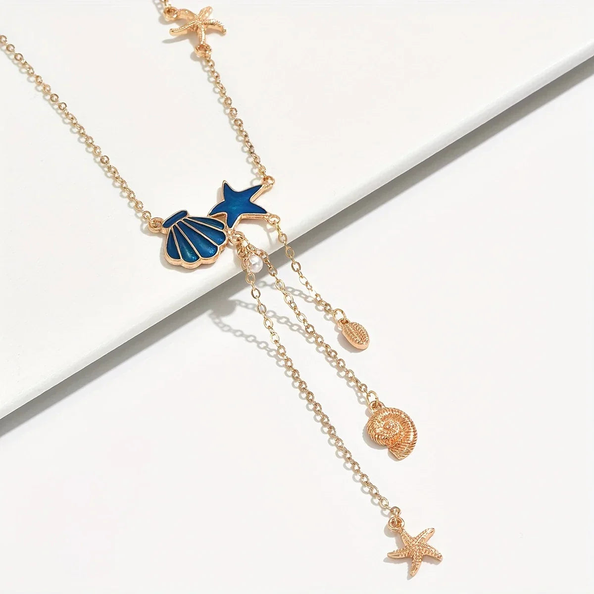 Elegante goldene Halskette mit Stern und blauer Muschel" could be rewritten as: "Stilvolle goldene Halskette mit Sternanhänger und blauer Muschel